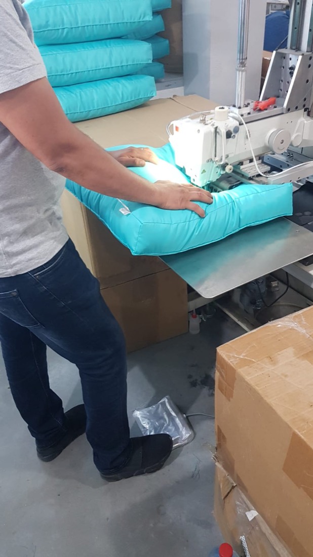Finition d'un coussin turquoise sur machine à coudre industrielle